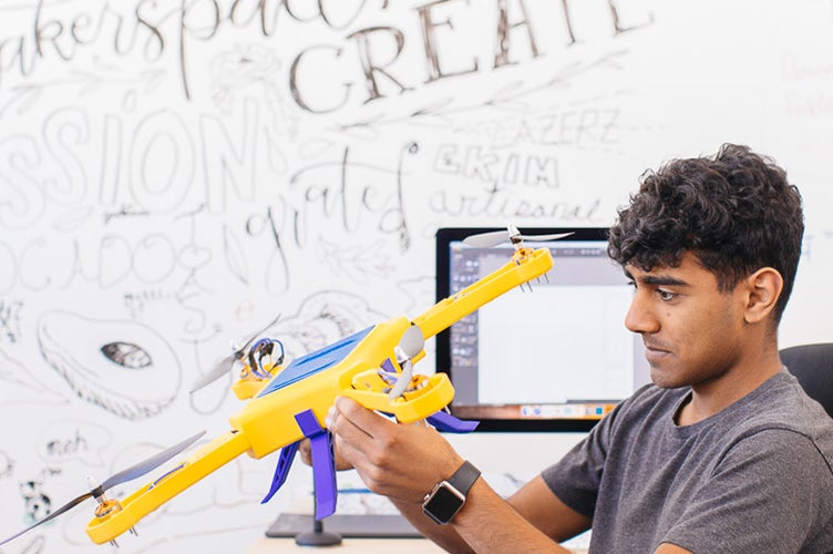 A student makes adjustments to a drone.