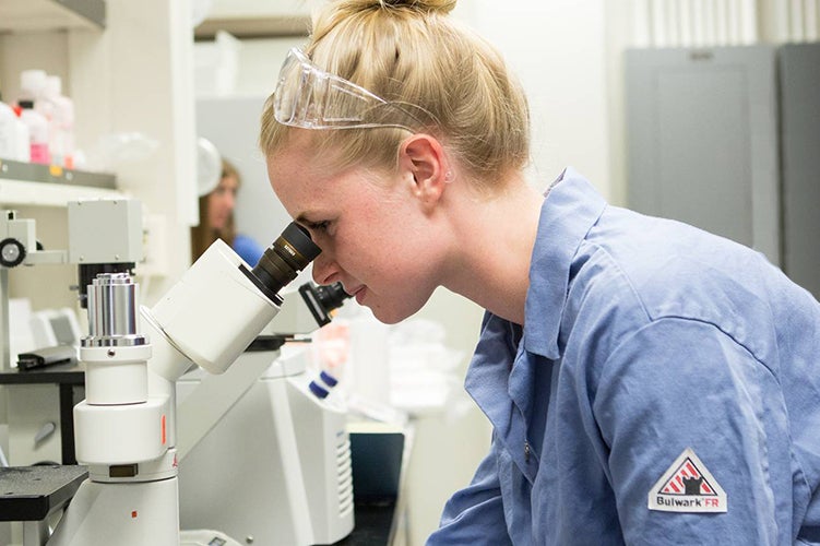 A female student looks into a microscope.