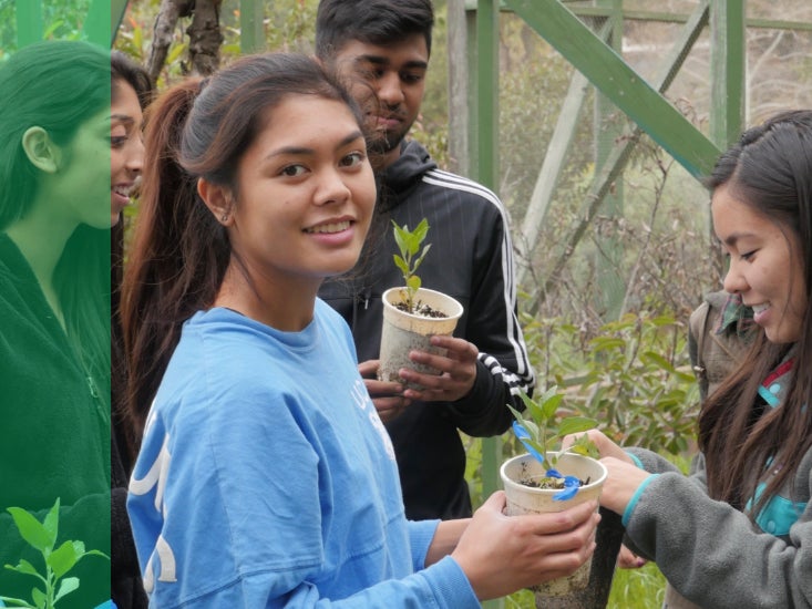 Un estudiante voluntario que trabaja con plantas sonríe para la cámara.