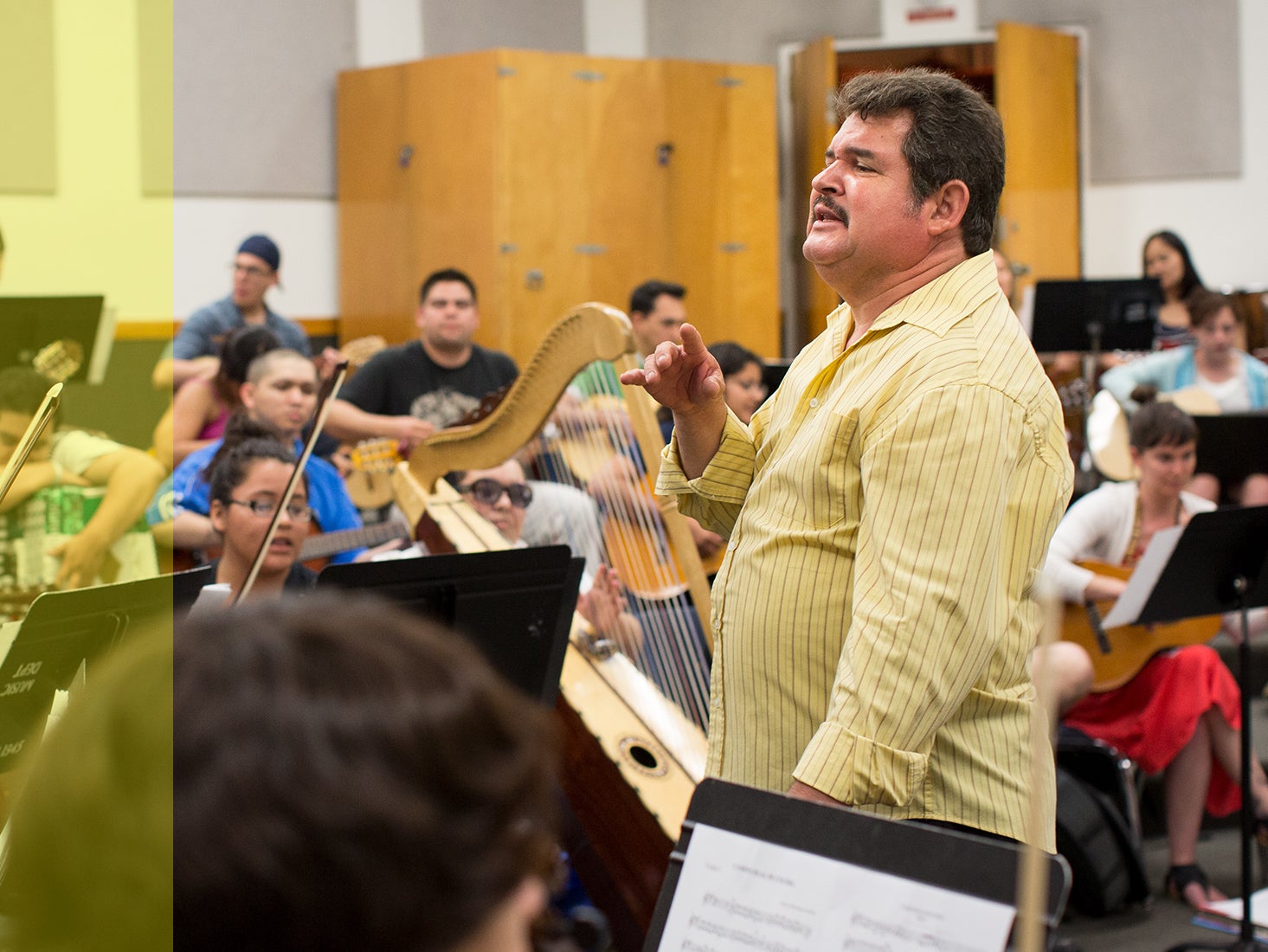 El arreglista, director, instructor y músico Jesús Guzmán dirige a los estudiantes en una orquesta.