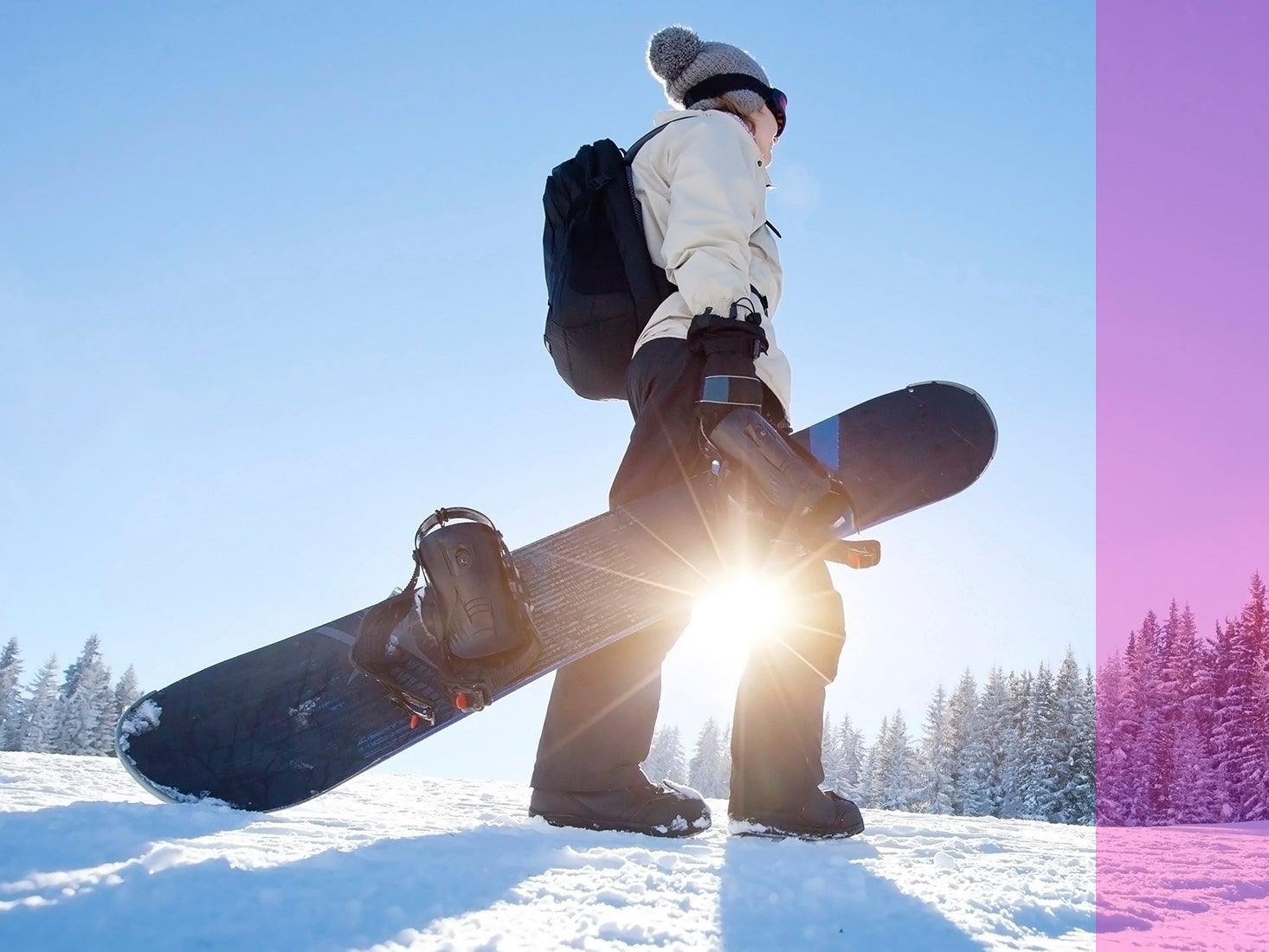 A snowboarder pauses to take in the view at the top of the mountain.