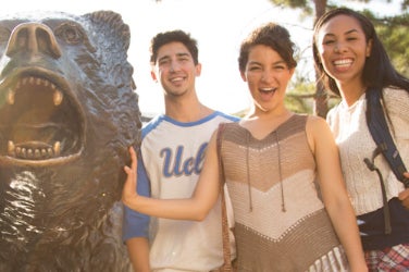 Los estudiantes sonríen junto a la estatua de The Bruin.