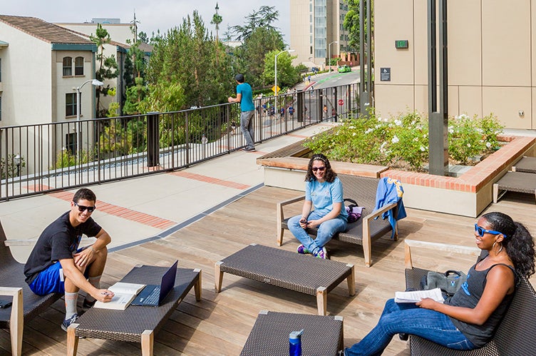 Students read and kick back on a sunny patio.