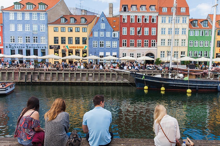 Students relax along a riverfront while studying abroad.