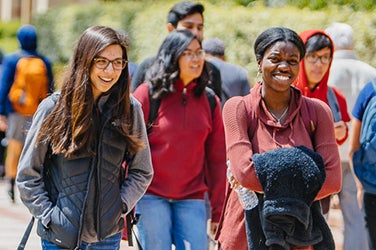 Estudiantes sonrientes caminan por el campus.