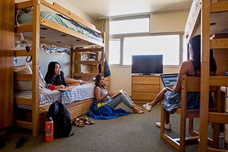 Students relaxing inside of a residence hall room.