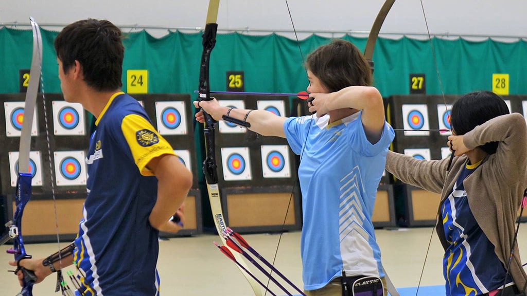 Los miembros de UCLA Archery apuntan sus arcos y flechas a la diana.