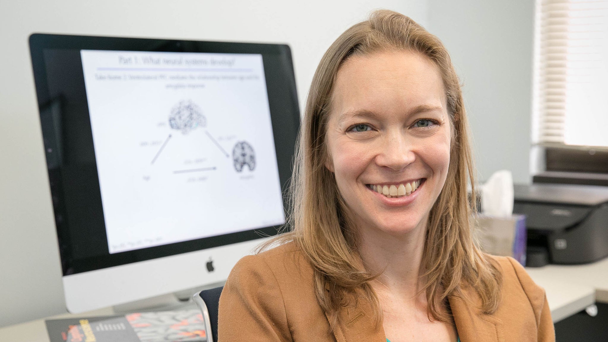 Assistant Professor of Psychology Jennifer Silvers pauses her computer research to smile for a photo.