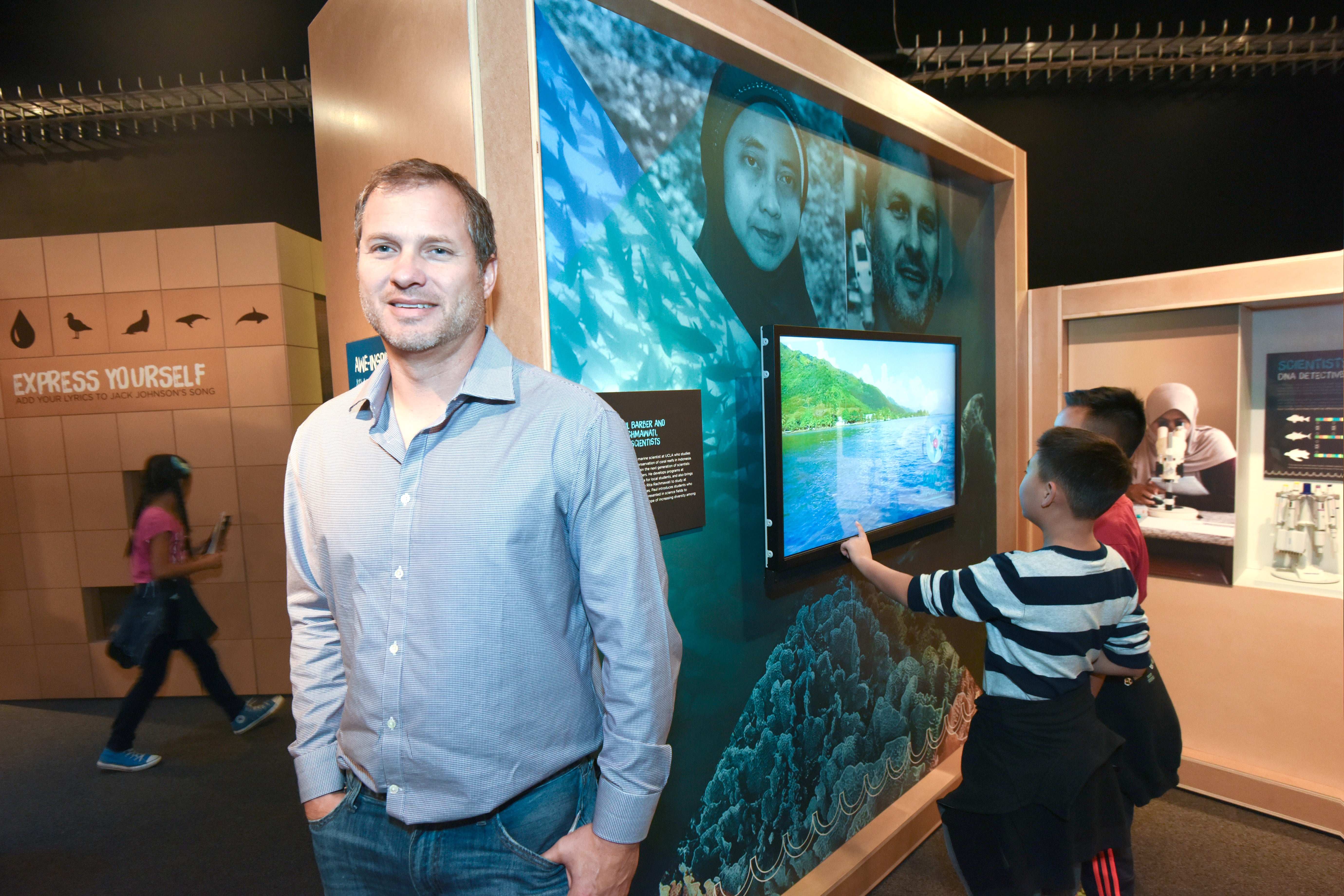 Professor Paul Barber at a science museum with children in the background.